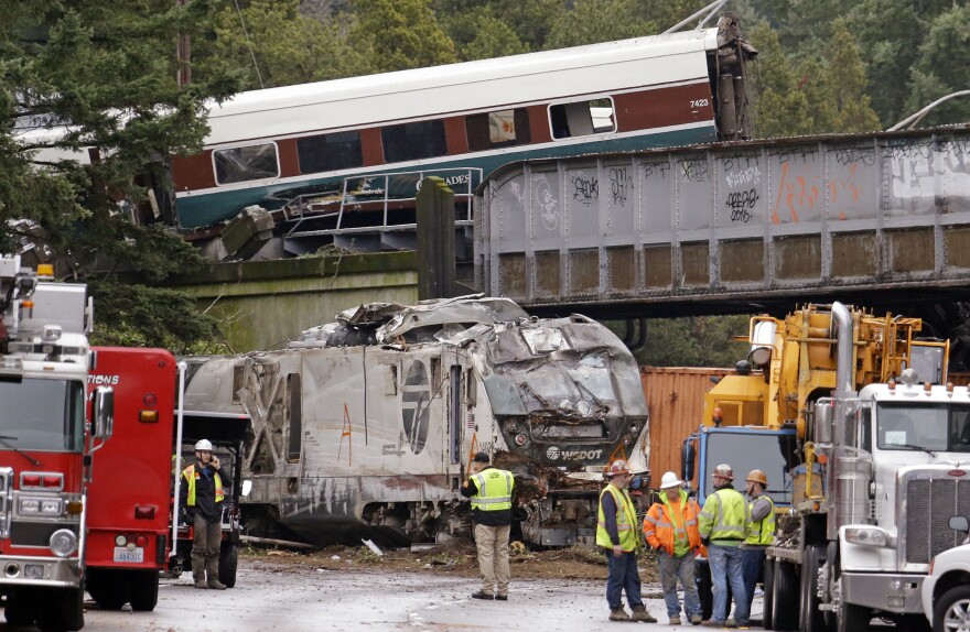 Cars from an Amtrak train lay spilled onto Interstate 5 below as some train cars remain on the tracks above on Monday in DuPont, Wash.