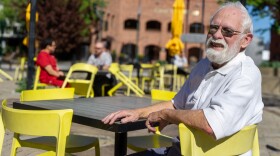 A man with white hair and a white beard sits outside in a yellow chair