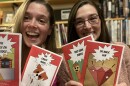 Brittany McGuire and Jackie Benson holding examples of their comic books, including "The Crazy Puppy" and "Two Rude Dudes. 