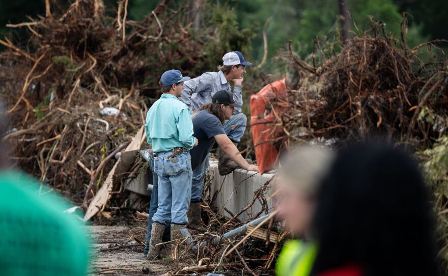 Onlookers look upstream at Big Sandy Creek from the damaged bridge on Sandy Creek Drive on Monday, July 7, 2025, in Leander, Texas. Flash floods damaged the bridge and homes in the surrounding community. Some residents in the area are confirmed dead or still missing.
