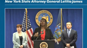 New York State Attorney General Leticia James stands at a podium with microphone.