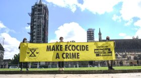 Members of Extinction Rebellion hold a banner reading 'Make Ecocide a Crime' in Parliament Square in London, England.