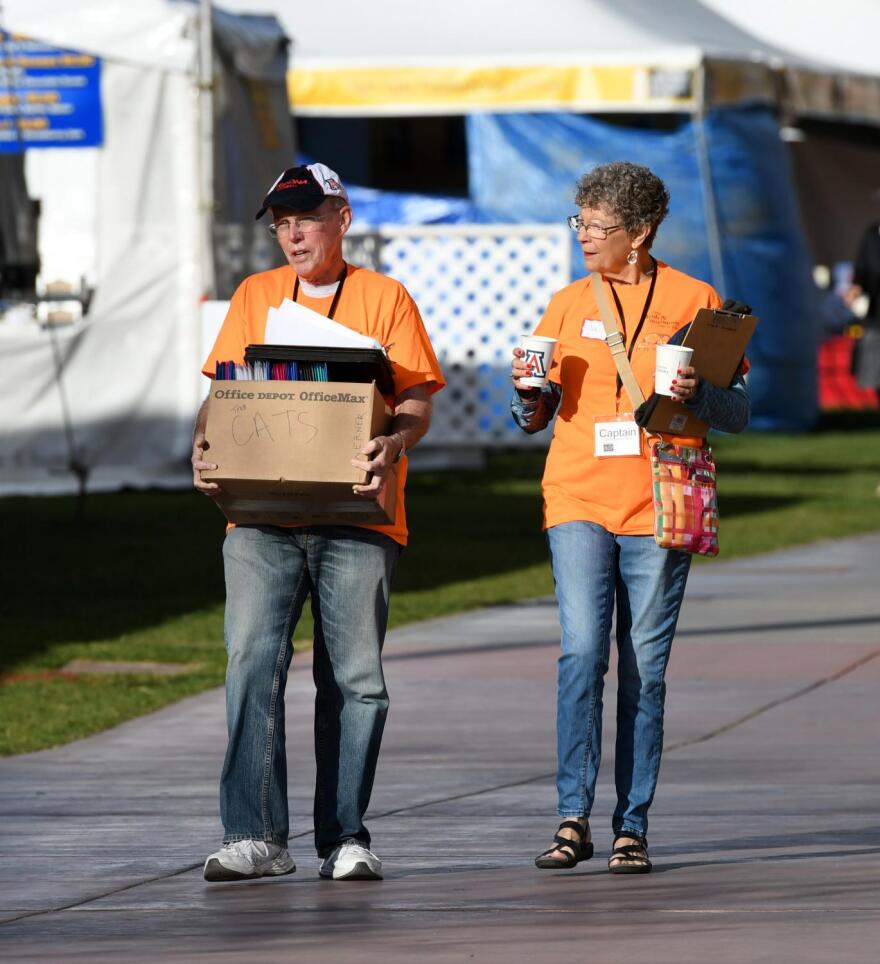 volunteer carrying a box and another carrying coffees