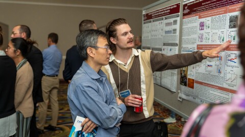 Eddie Rygalski, a PhD student in Virginia Tech's translational biology medicine and health program (right), discusses his poster with another conference participant at the International Biochemistry of Exercise Conference in Roanoke.