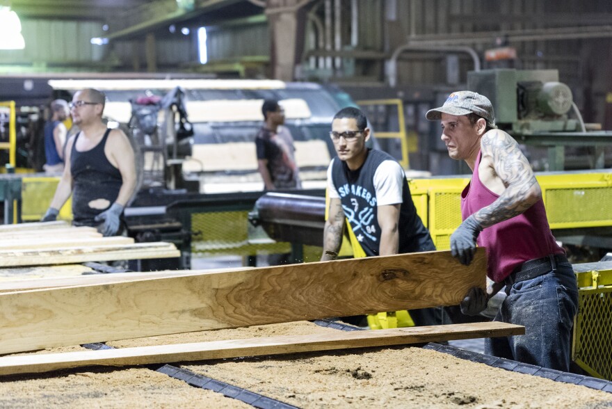 Workers check and sort boards coming out of the mill.