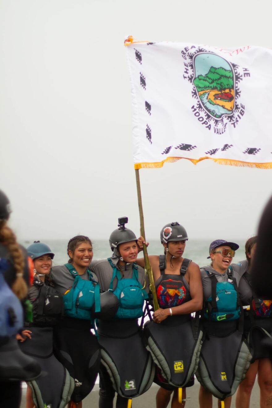 After completing the 30 day, 310-mile descent of the newly undammed Klamath River, Indigenous youth celebrate while holding the Hoopa Valley Tribal flag. L to R: Isqotsxoyan Scott, Kiahna Allen, Julian Rogers, ‘A:de’ts Rogers, and Ruby Williams.