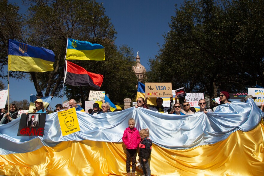 A crowd in front of the Texas Capitol holding Ukrainian flags and signs calling for a stop to the war. 