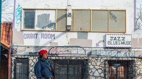 A woman stands in front of a building with graffiti and a sign that says Orbit Room, Jazz Blues Music