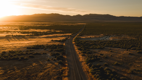 Aerial view of a sunrise over a mostly-empty valley with a road winding through the center.