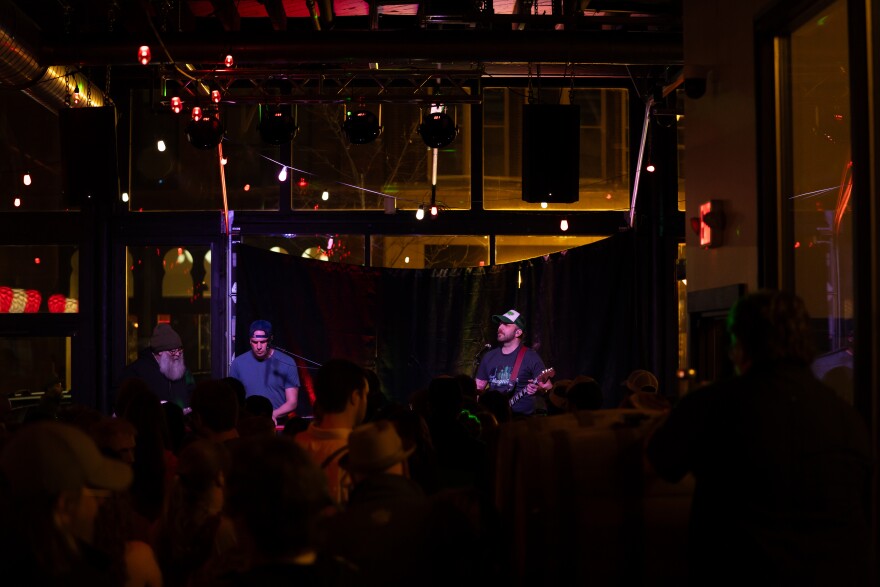 A band performing on a stage as seen from the middle of the audience