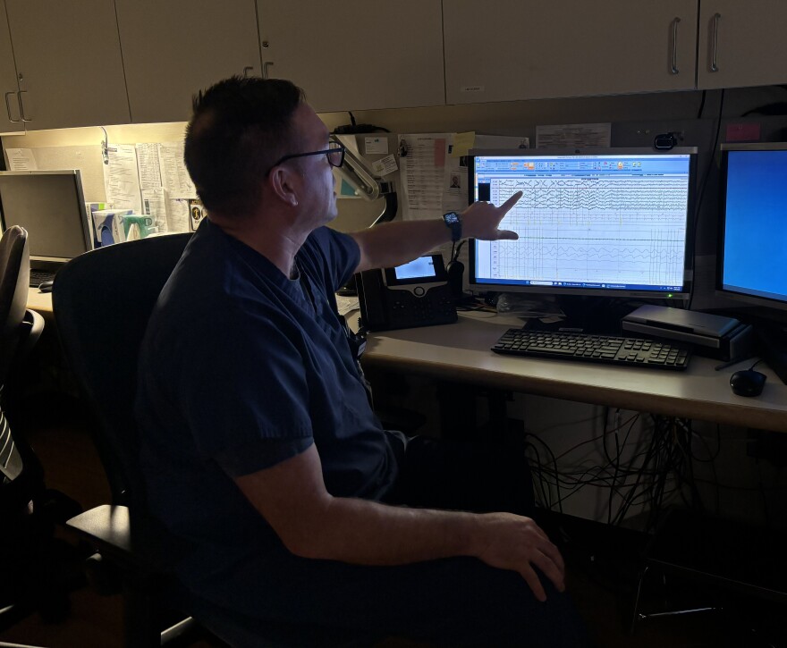 Clinic Supervisor Mark Kingen gestures to a screen that shows an example of all the things the sleep techs track including eye movements, heart rate, brain waves, limb movements, whether or not patients are clenching or grinding their teeth, and many more.