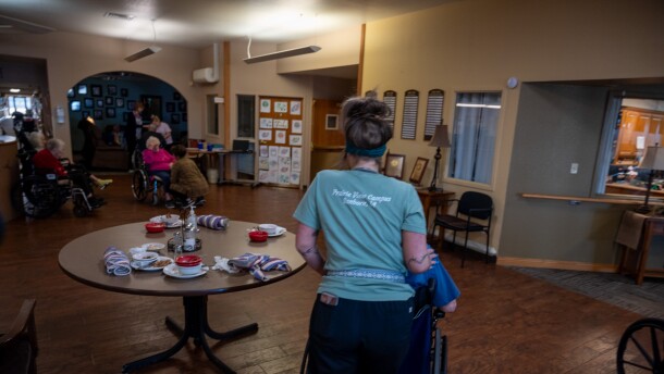 A worker at the Prairie View Nursing Home in Sanborn, Iowa, wheels a resident after lunch. The nursing home has faced chronic staffing shortages that were made worse by the COVID-19 pandemic.