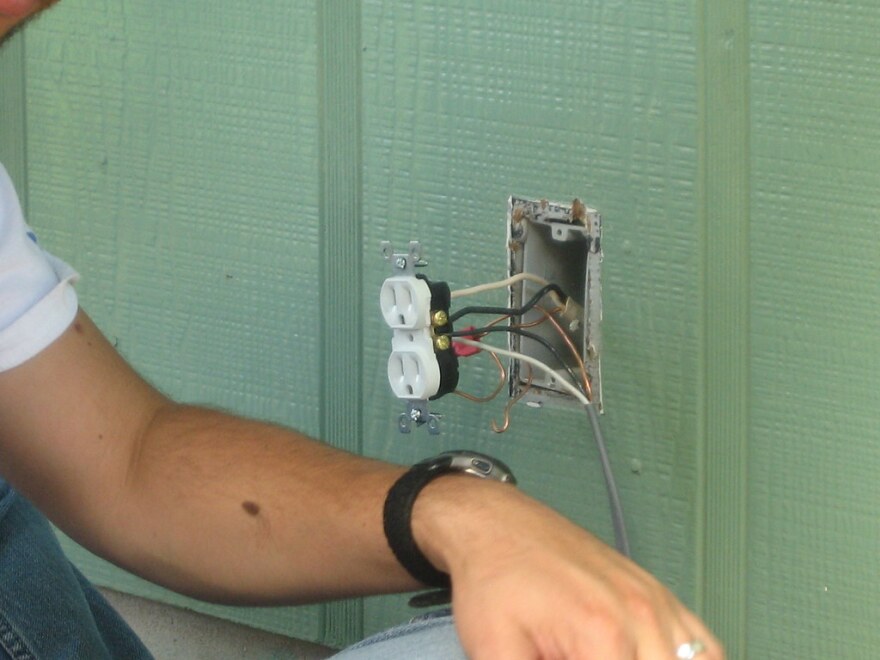 Man works on electrical outlet outside