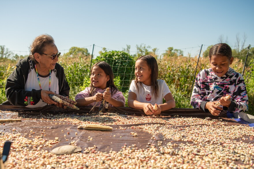 A photo of Native Americans processing corn in the "Legacy of Land" exhibit.