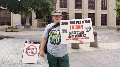 Conserve Ohio volunteer Kim Kinder-Smith stands outside Columbus City Hall on July 22, 2026 ahead of a public hearing on proposed data center regulations in the city. Kinder-Smith was gathering signatures for a measure to ban large data centers.