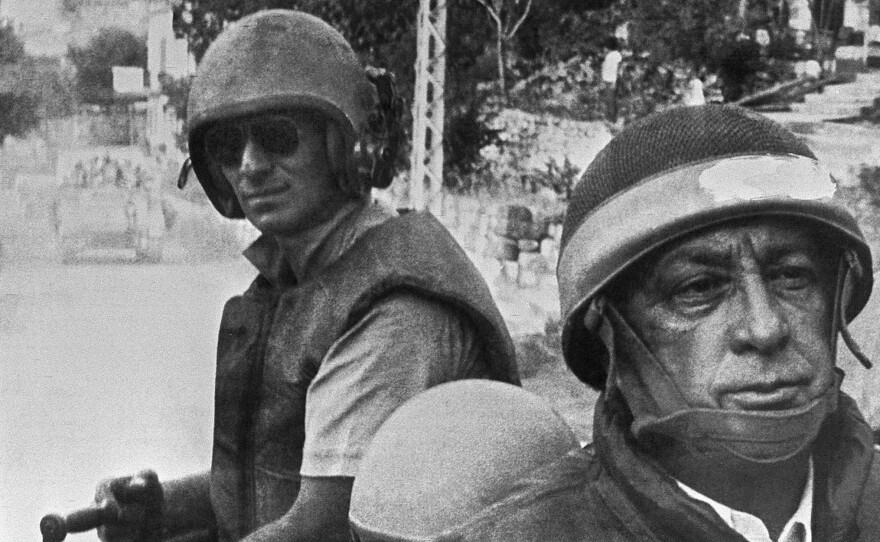 Israeli Defense Minister Ariel Sharon (right), in combat helmet and flak jacket, rides with his troops on June 15, 1982, as they head deeper into Lebanon. The Israelis drove Arafat and his Palestine Liberation Organization out of Lebanon, but Sharon was later found "indirectly responsible" for the killings of hundreds of Palestinian civilians carried out by a Lebanese militia allied with Israel.