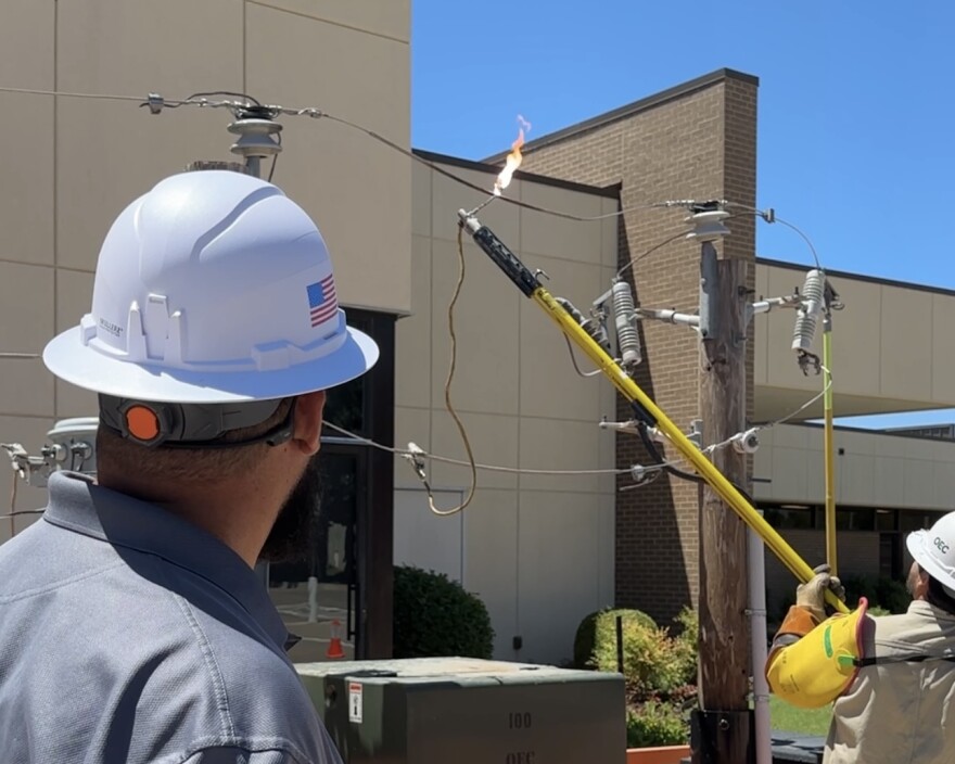Tony Ramirez, a lineman with 12 years of experience, touches a hot dog to a live powerline to show the dangers of electricity at the OAEC headquarters in Oklahoma City on May 20, 2025.