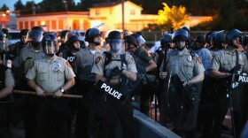 Police stand watch in August 2014 as demonstrators protest the shooting death of Michael Brown in Ferguson, Mo.