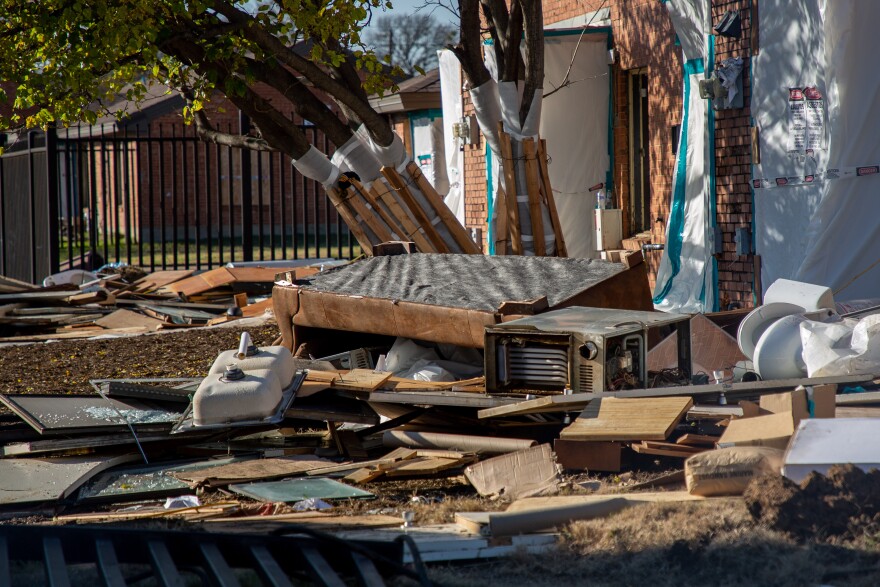 A pile of trash spreads haphazardly in front of a red brick apartment building at Cavile Place. There's what appears to be a couch, a torn out sink, an AC unit, a toilet and broken glass on a bed of other trash.