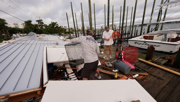 People retrieve belongings from a collapsed boat house in the aftermath of Hurricane Isaias in Destin, Fla., Saturday, Oct. 10, 2026. (AP Photo/Gerald Herbert)