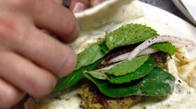 Lucy Wang rolls up an Iranian kubideh wrap sandwich in the prep area. The sandwich is made with homemade bread and grilled ground beef mixed with turmeric, cumin, cinnamon, mint, basil and other spices. Conflict Kitchen is a takeout cafe designed and run by three artists hoping to open a conversation about countries in conflict with the U.S. by serving one dish from a particular country a month.