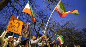 Protesters hold up placards and flags as they demonstrate outside the Iranian Embassy in London, Monday, Jan. 12, 2026.