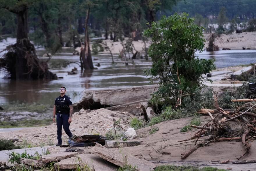 A police officer walks along the Guadalupe River after a series of storms on Friday, July 17, 2026, in Kerrville, Texas. (AP Photo/Gerald Herbert)