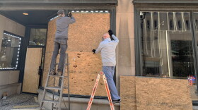 Workers install plywood over windows of the Windsor Jewelry store in downtown Indianapolis on Monday, Nov. 2.