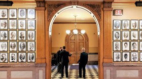 Three men talking outside the door to the Kansas House of Representatives.