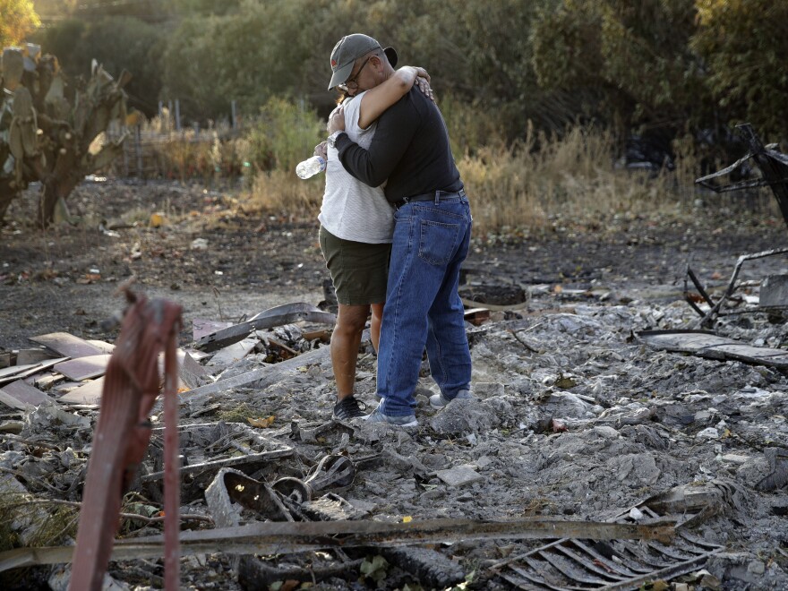 Justo and Bernadette Laos hug while looking through the charred remains of the home they rented that was destroyed by the Kincade Fire near Geyserville, Calif.