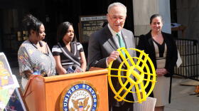 U.S. Senator Chuck Schumer (Center) holds a fail safe device for grease traps. Credit James Brown / WXXI