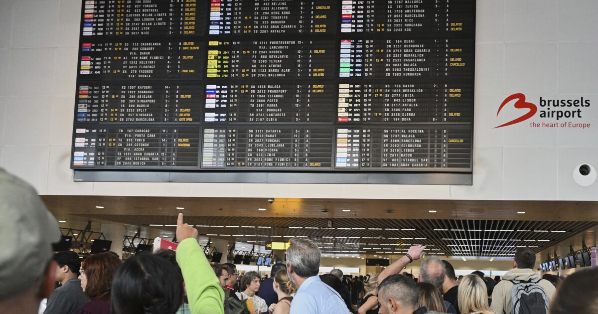 An airport employee points at a departure board after a cyber attack caused delays at Brussels International Airport in Zaventem, Belgium, Saturday, Sept. 20, 2025.