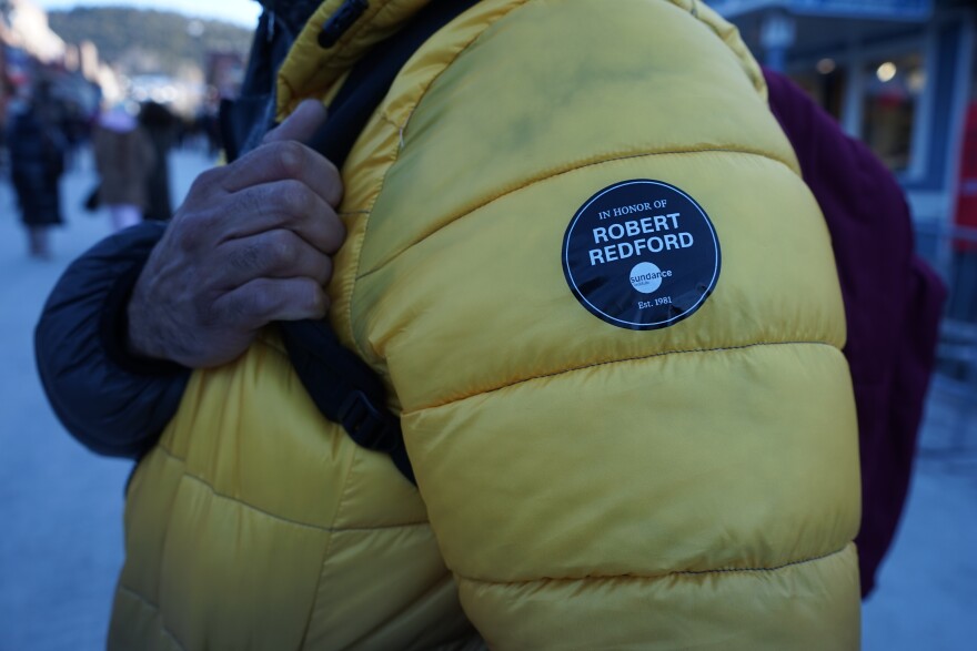 The arm of yellow winter jacket showcases a commemoration of Sundance founder Robert Redford.