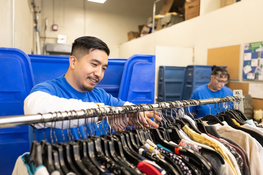 A Goodwill employee sorts through a rack of donated clothing.