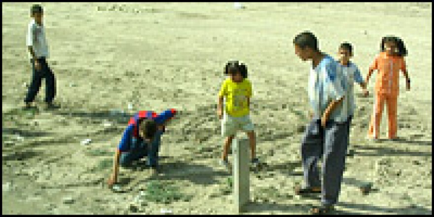 Children run up to a mortar round on the side of a highway as Americans searching for roadside bombs move in to inspect it. The shell turned out to be a dud.