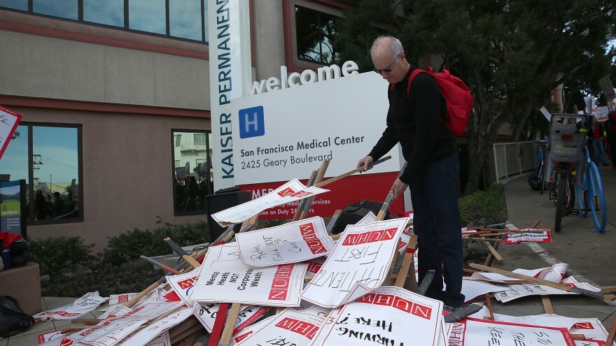 A Kaiser mental health worker with the National Union of Healthcare Workers looks through a pile of signs Monday during day one of a week-long demonstration outside of a Kaiser Permanente hospital in San Francisco.