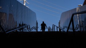 A person walking up stairs towards large silver walls.