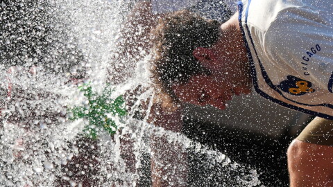  A person cools off with his head in a water spray 