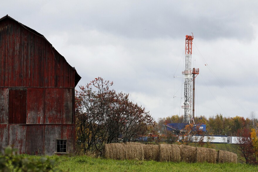 A natural gas drilling rig near an old barn.