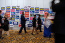 People walk by a wall that is plastered with campaign signs