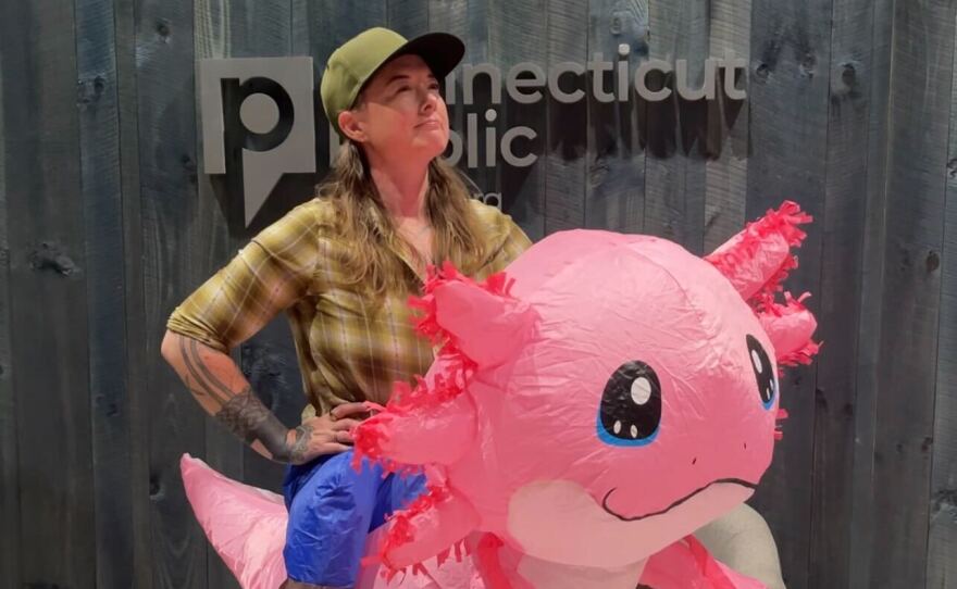 Chion Wolf getting ready to surprise Connecticut Public’s president and CEO, Mark Contreras with a singing telegram (while wearing an inflatable axolotl costume).