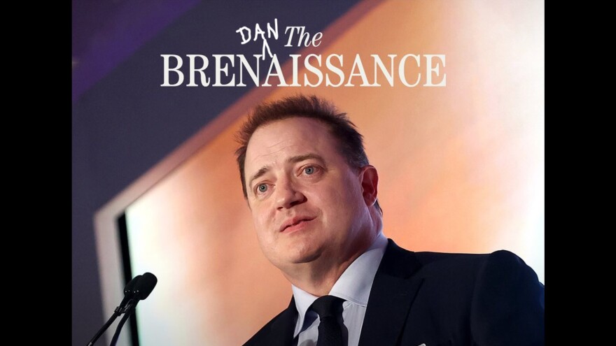 A man in a suit and tie stands behind a lectern with a microphone.