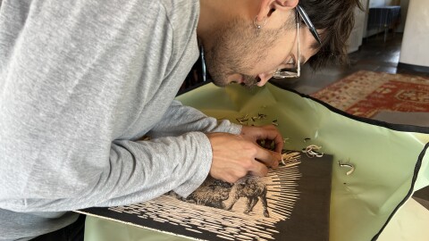 Jacob Gutierrez carves a portrait of cows onto a wood block as part of his book, Sacred Herd.