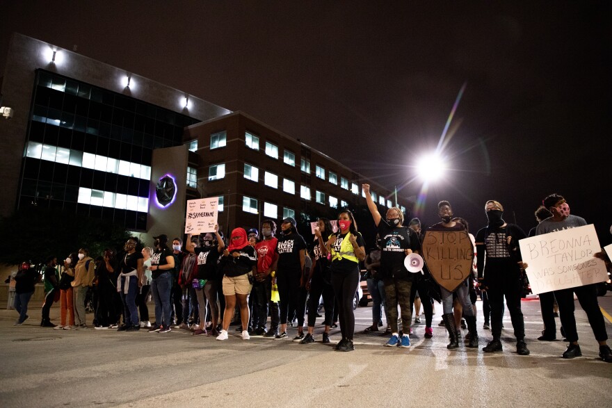 Photo of protesters in a line blocking the intersection in front of Dallas Police Headquarters.