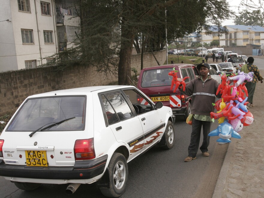 A vendor sells toys to drivers caught in Nairobi traffic. Drivers who get traffic reports by text message could avoid congested routes or consider taking back streets, many of which are underused.