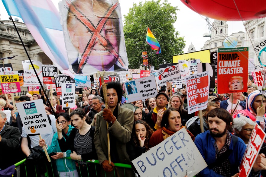 Protesters gather behind a barrier on Whitehall road in Central London during a demonstration against the Trump.