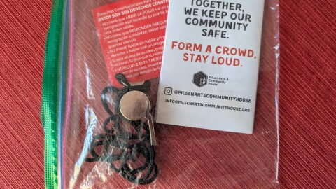 A silver whistle and informational pamphlet are in a plastic ziplock bag. 