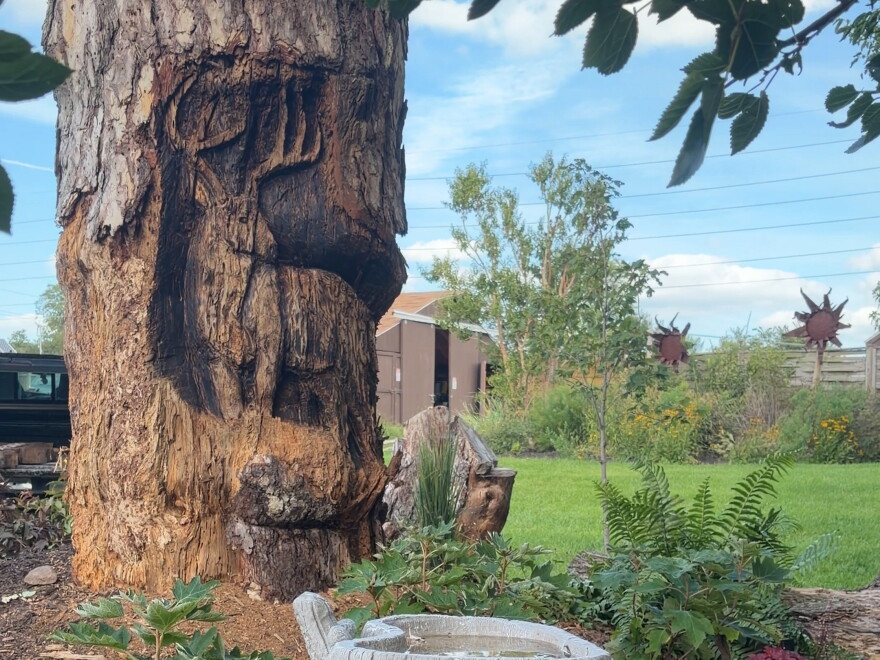 A deer with antlers is carved into a tree stump