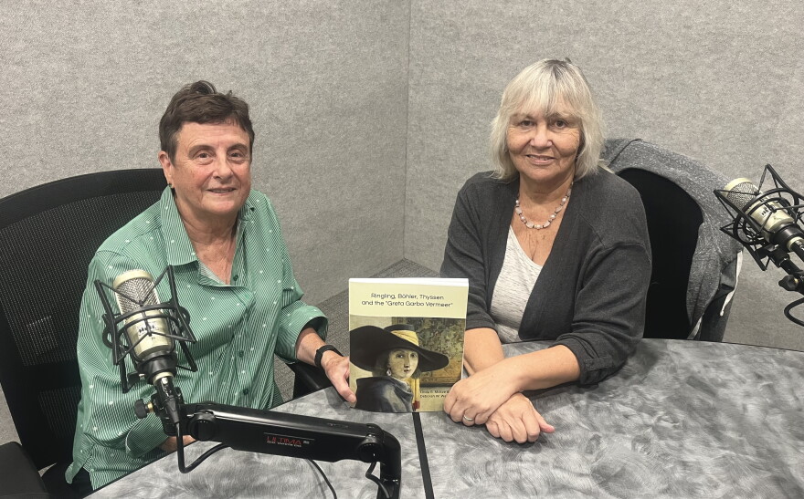Two women sit at a desk with microphones and smile at the camera. They hold their book entitled "Ringling, Bohler, Thyssen and the Greta Garbo Vermeer".