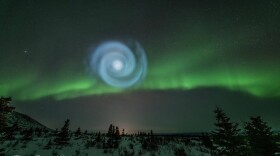 a spiral blue image in the sky with auroras in the background